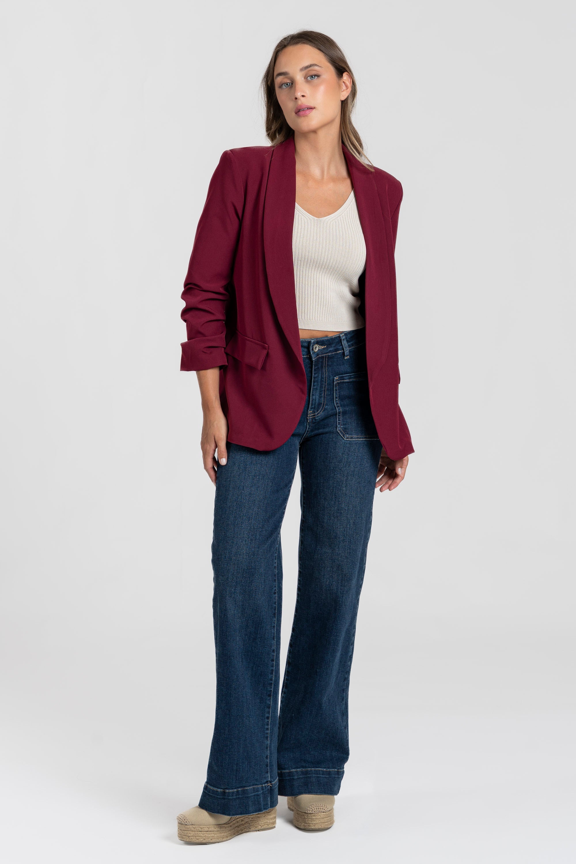 Modèle en blazer femme chic bordeaux avec un pantalon en denim, idéal pour un look casual et chic.