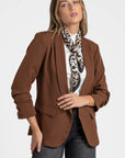 Détail d'un blazer femme chic marron mis en avant sur une femme avec un style moderne.