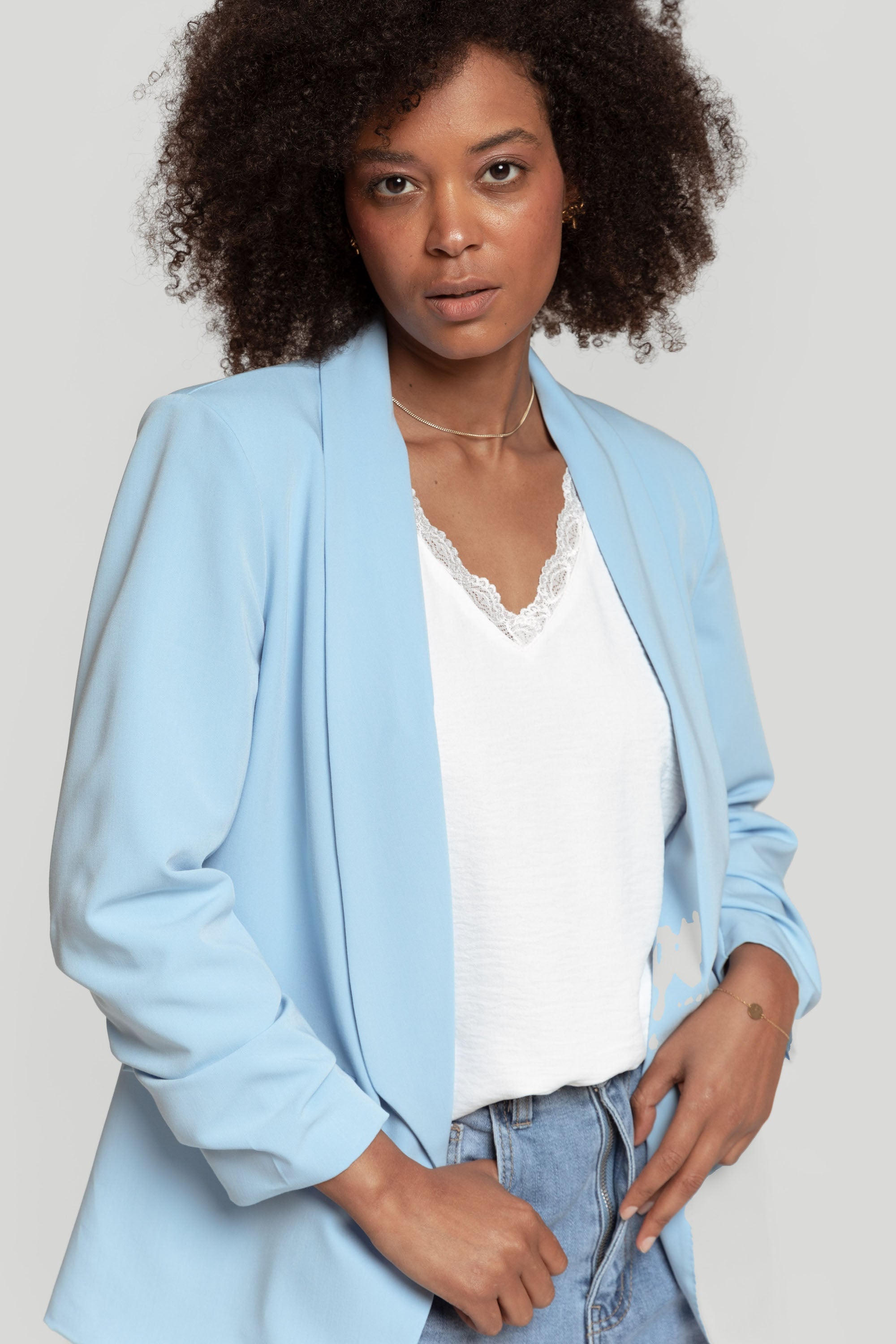 Femme présentant un blazer femme chic bleu clair, stylisé avec un jean pour un look casual moderne.