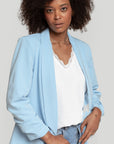 Femme présentant un blazer femme chic bleu clair, stylisé avec un jean pour un look casual moderne.