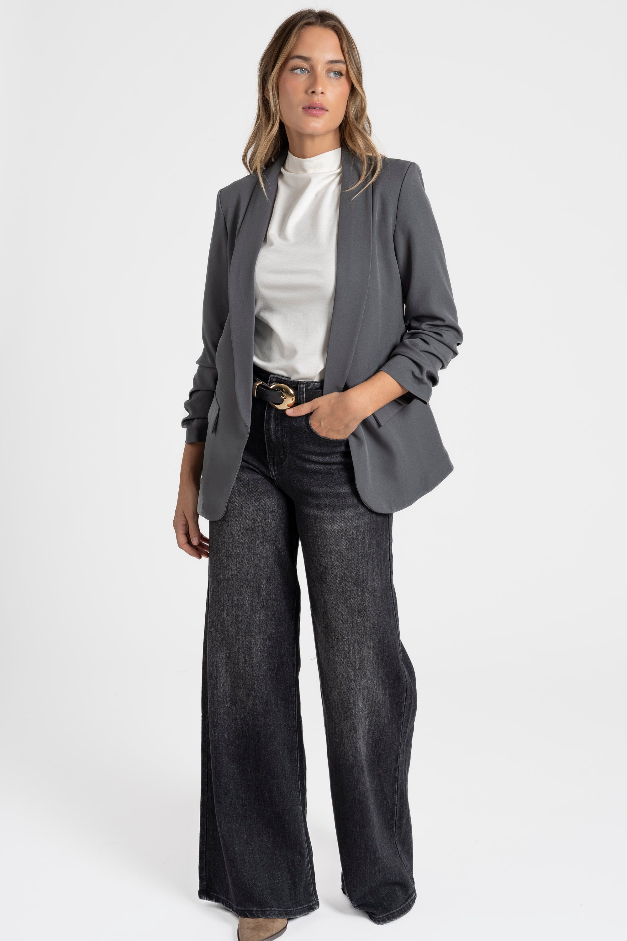 Modèle portant un blazer femme chic élégant avec manches froncées, associé à un pantalon large, parfait pour un look décontracté.