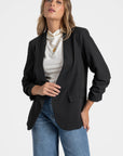 Femme portant un blazer femme chic noir, avec un haut blanc et un look sophistiqué.