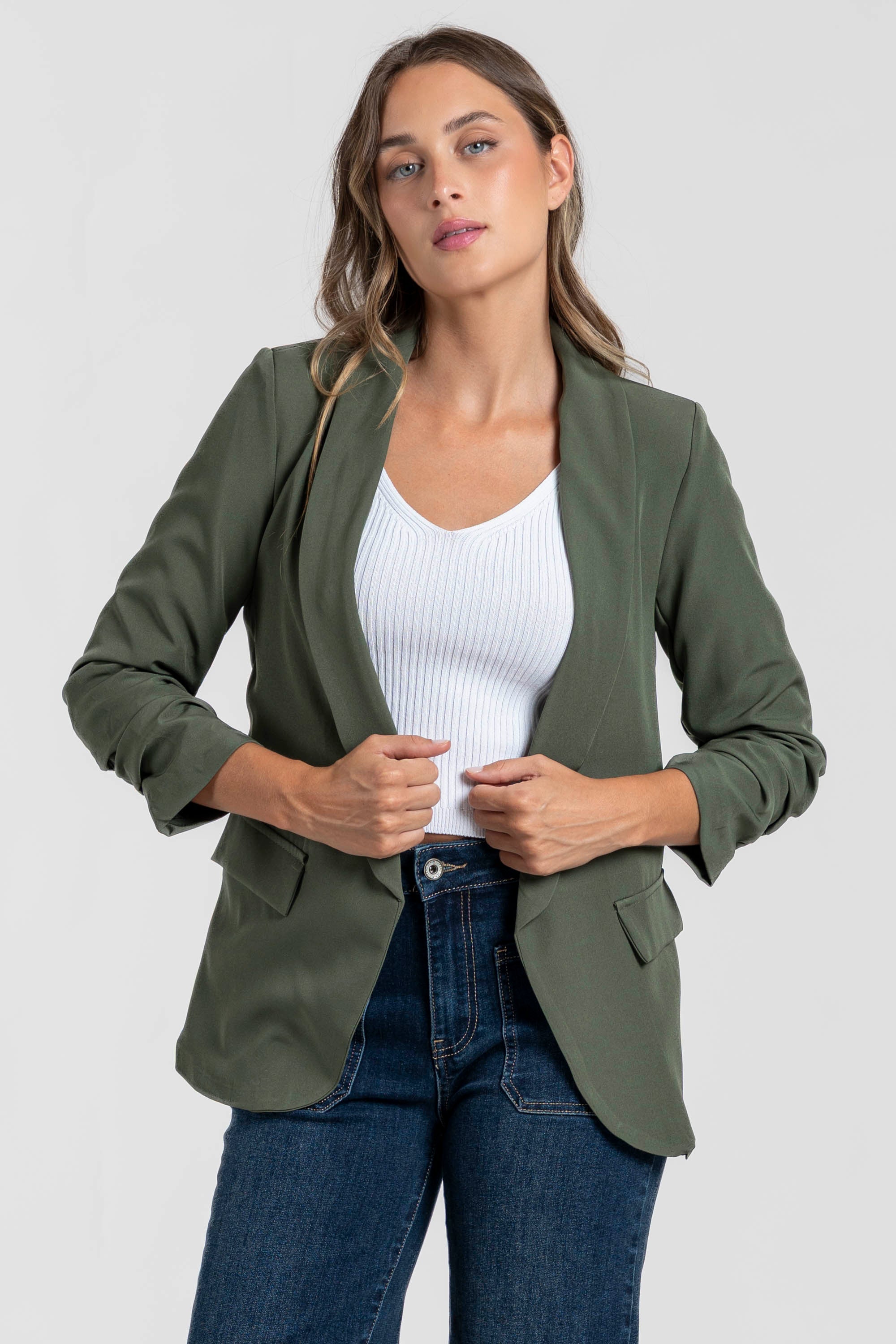 Femme dans un blazer femme chic vert olive, avec un haut blanc pour un style travaillé.