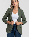 Femme dans un blazer femme chic vert olive, avec un haut blanc pour un style travaillé.