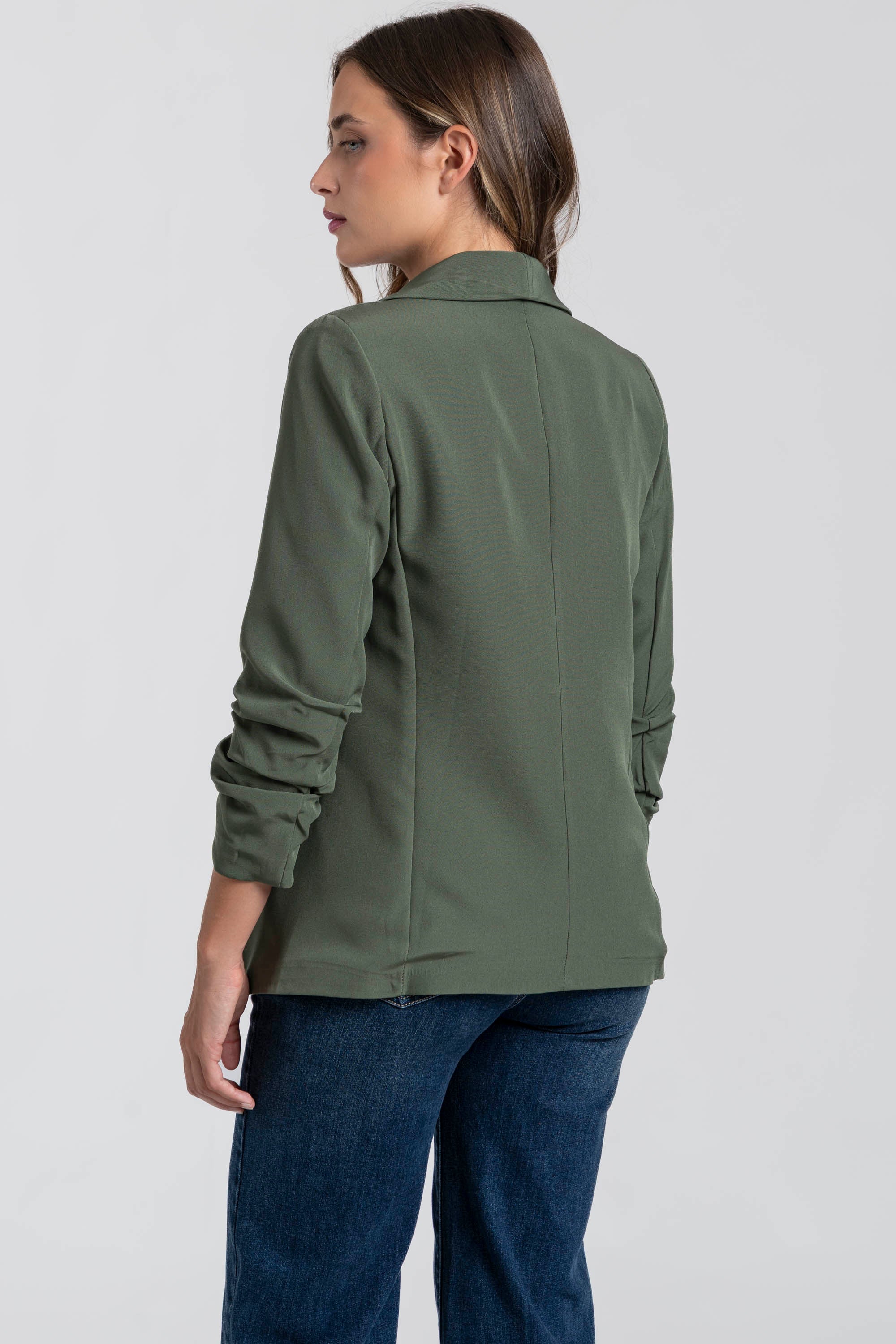 Profil arrière d'une femme dans un blazer femme chic vert, soulignant la qualité du tissu.