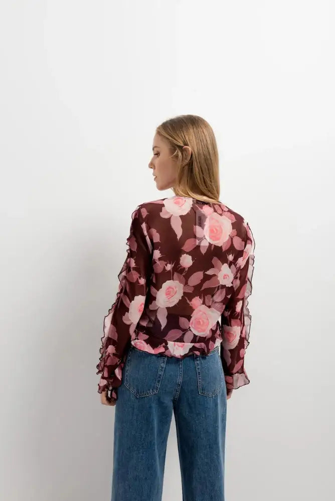 Femme portant une blouse à volants imprimée florale avec roses roses et jeans bleus