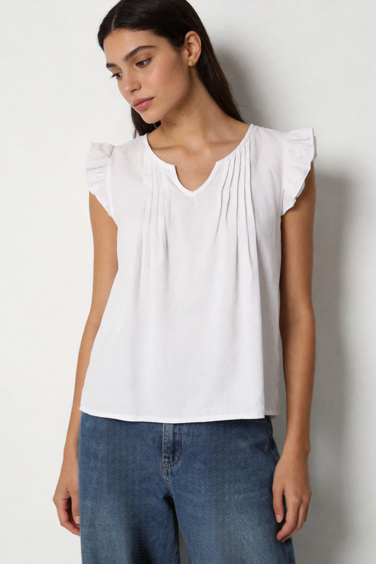 Blouse blanche fluide à col V fendu et volants aux épaules, portée de face