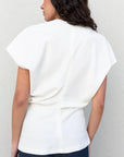 Image d'une femme de dos en blouse blanche minimaliste, prête à se démarquer avec élégance. La blouse blanche femme apporte une note chic à votre garde-robe.