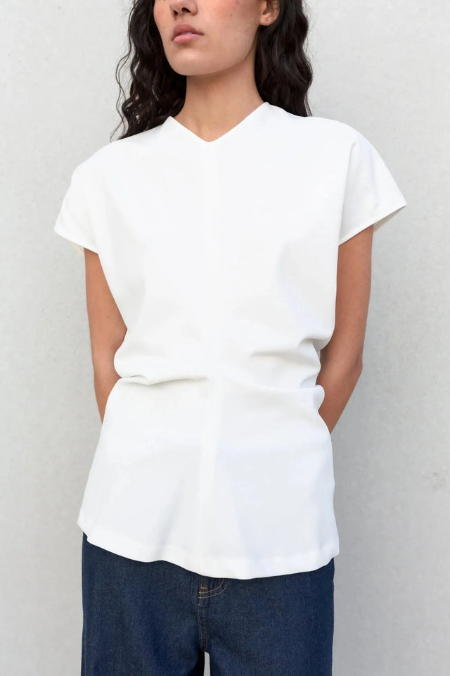 Vue rapprochée d'une femme en blouse blanche col V, stylée avec un look décontracté. Un choix parfait pour une blouse blanche femme élégante et confortable.