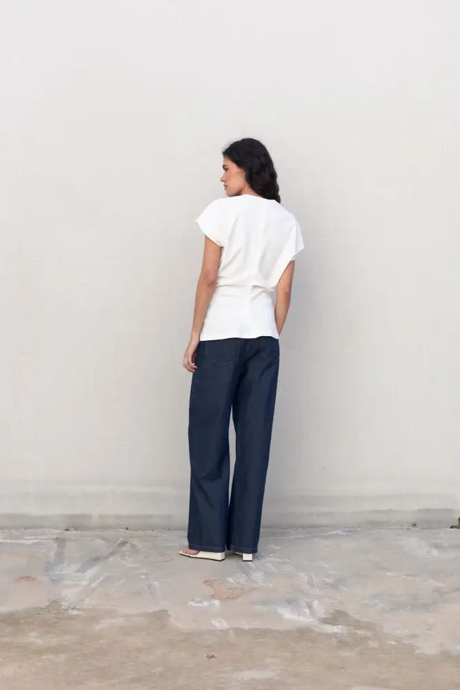 Femme portant une blouse blanche élégante col V minimaliste et pantalon large bleu foncé