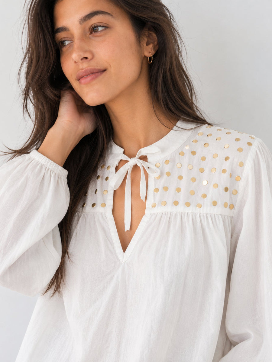 Détail encolure V sur blouse blanche pastilles dorées