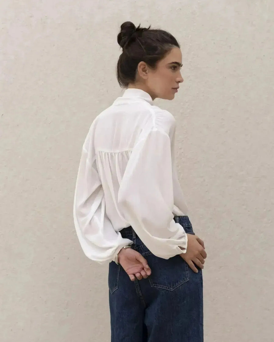 Femme portant une blouse fluide élégante blanche à nouer, livraison rapide