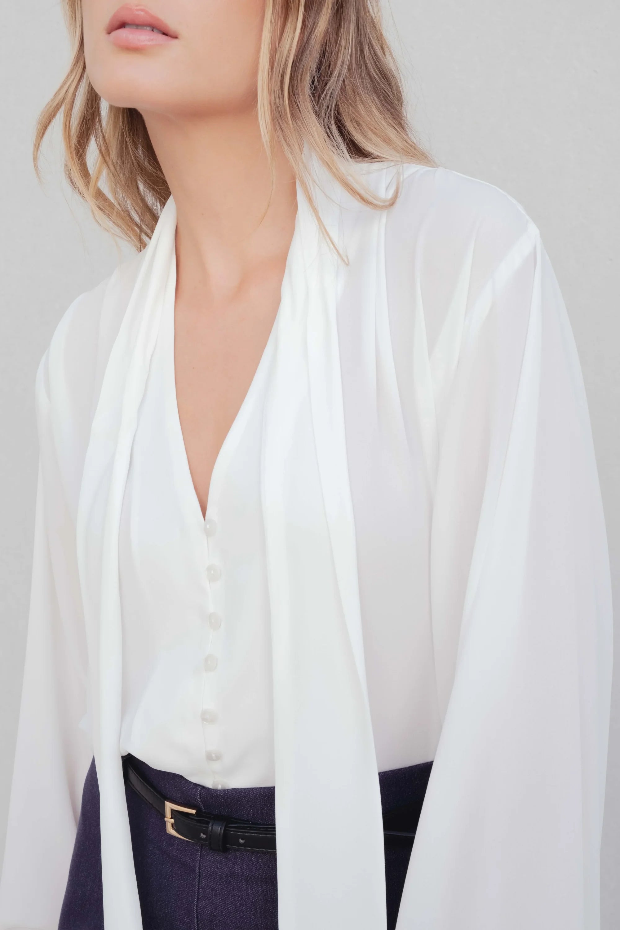 Femme portant une blouse fluide élégante blanche à nouer, livraison rapide