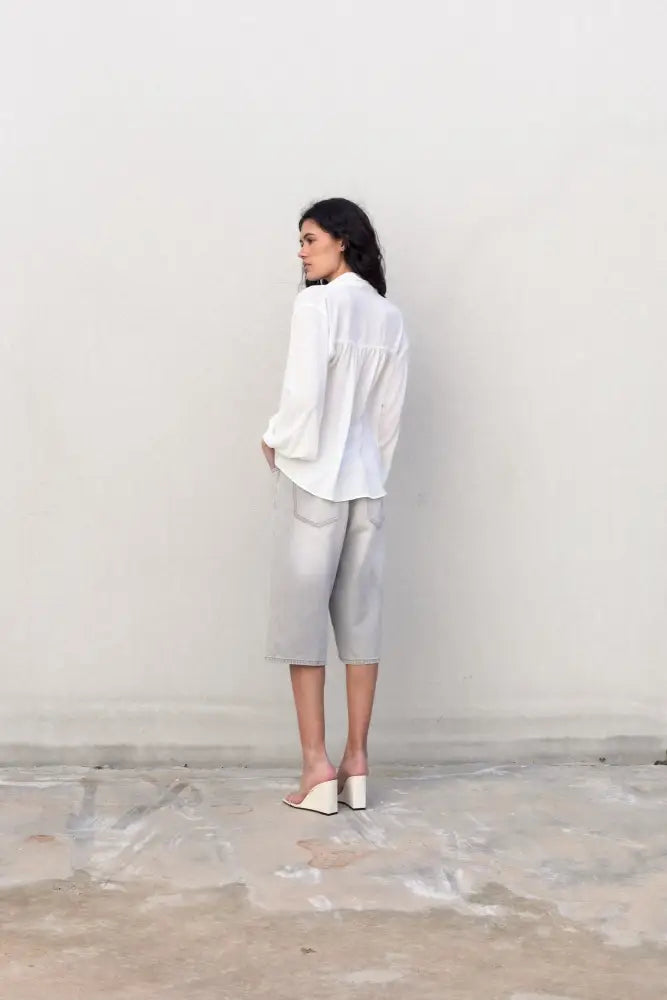Femme portant une blouse fluide élégante blanche à nouer avec shorts gris et sandales à talons