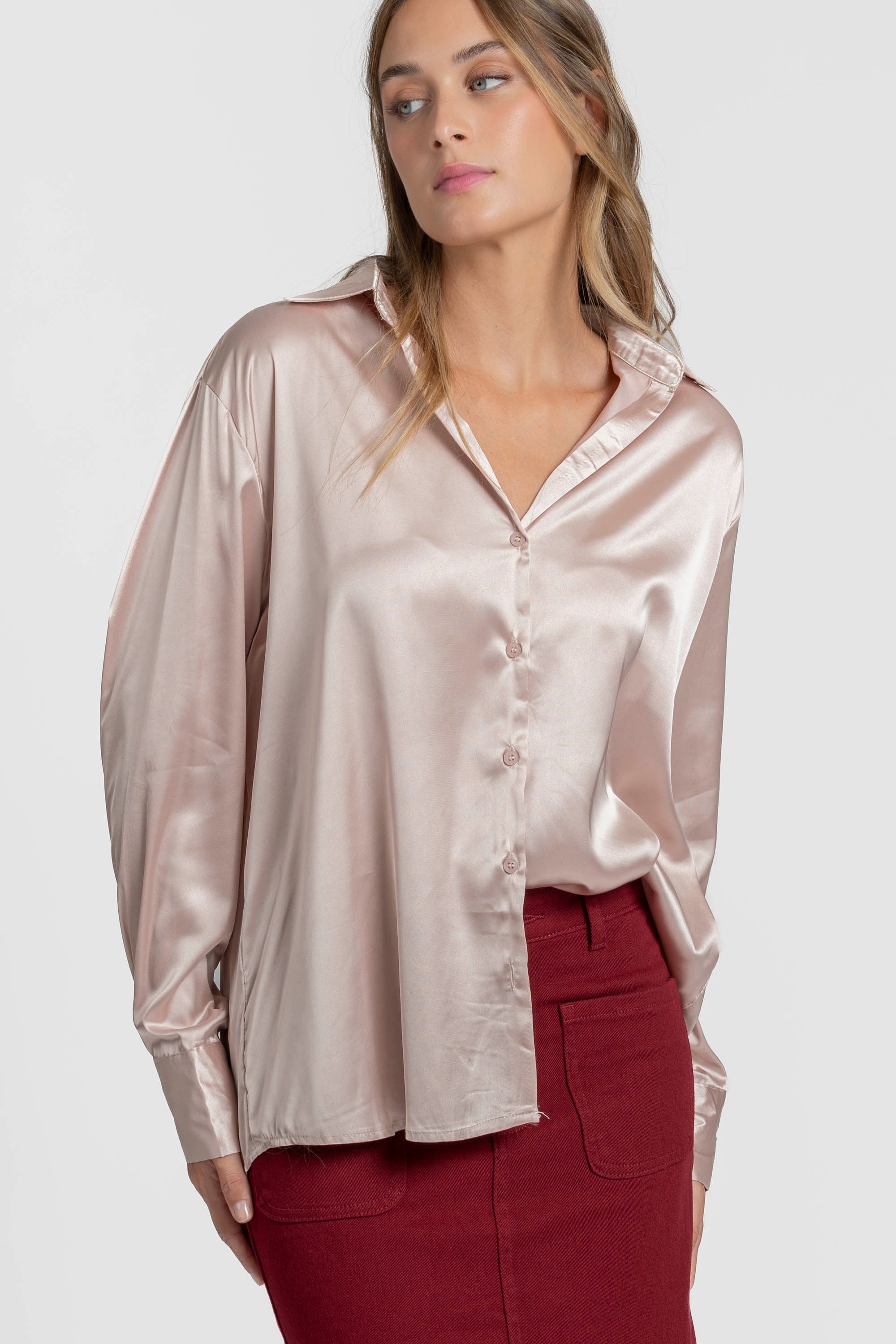 Blouse satinée élégante pour femme avec coupe ample et col chemise, portée par un modèle au teint frais, associée à une jupe rouge.