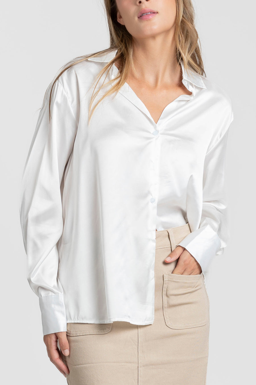 Détails rapprochés d'une blouse satinée femme élégante blanche avec col chemise, portée par un modèle.