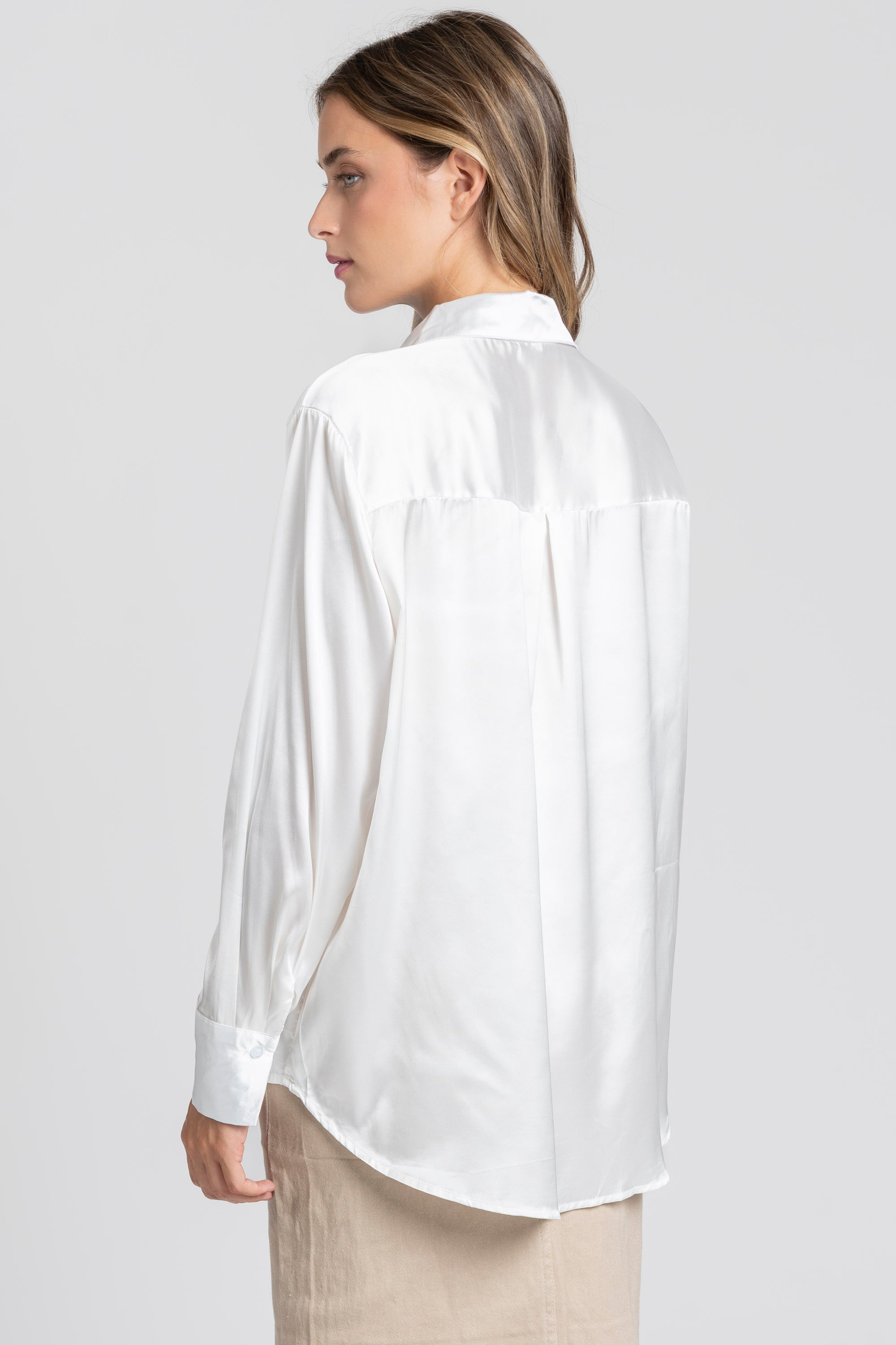 Vue arrière d'une blouse satinée femme élégante blanche, mettant en avant le col chemise et le drapé sur un modèle.