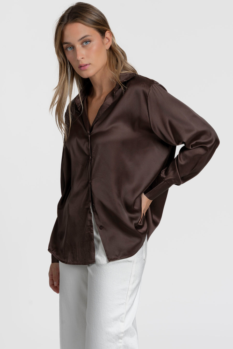 Blouse satinée femme élégante en brun, à col chemise, portée avec un pantalon en lin, dégageant une allure moderne.
