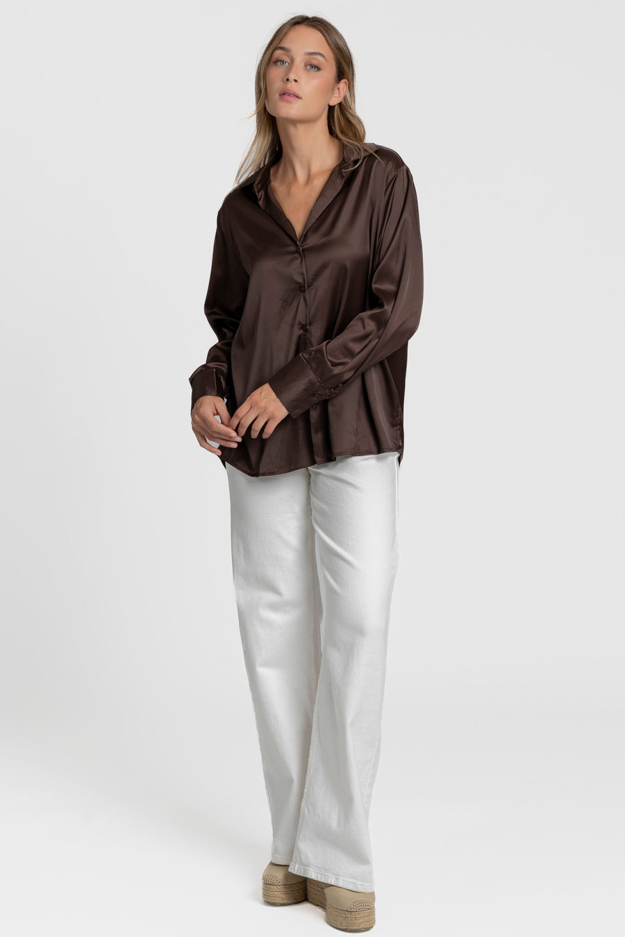 Modèle en blouse satinée femme élégante de couleur brun, associée à un style chic avec des pantalons clairs.