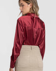 Détails du dos d'une blouse satinée femme élégante en rouge, mettant en avant le col chemise et le drapé fluide.