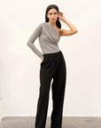 Femme mettant en avant son body asymétrique, combiné avec un pantalon noir, pour un look chic et moderne.