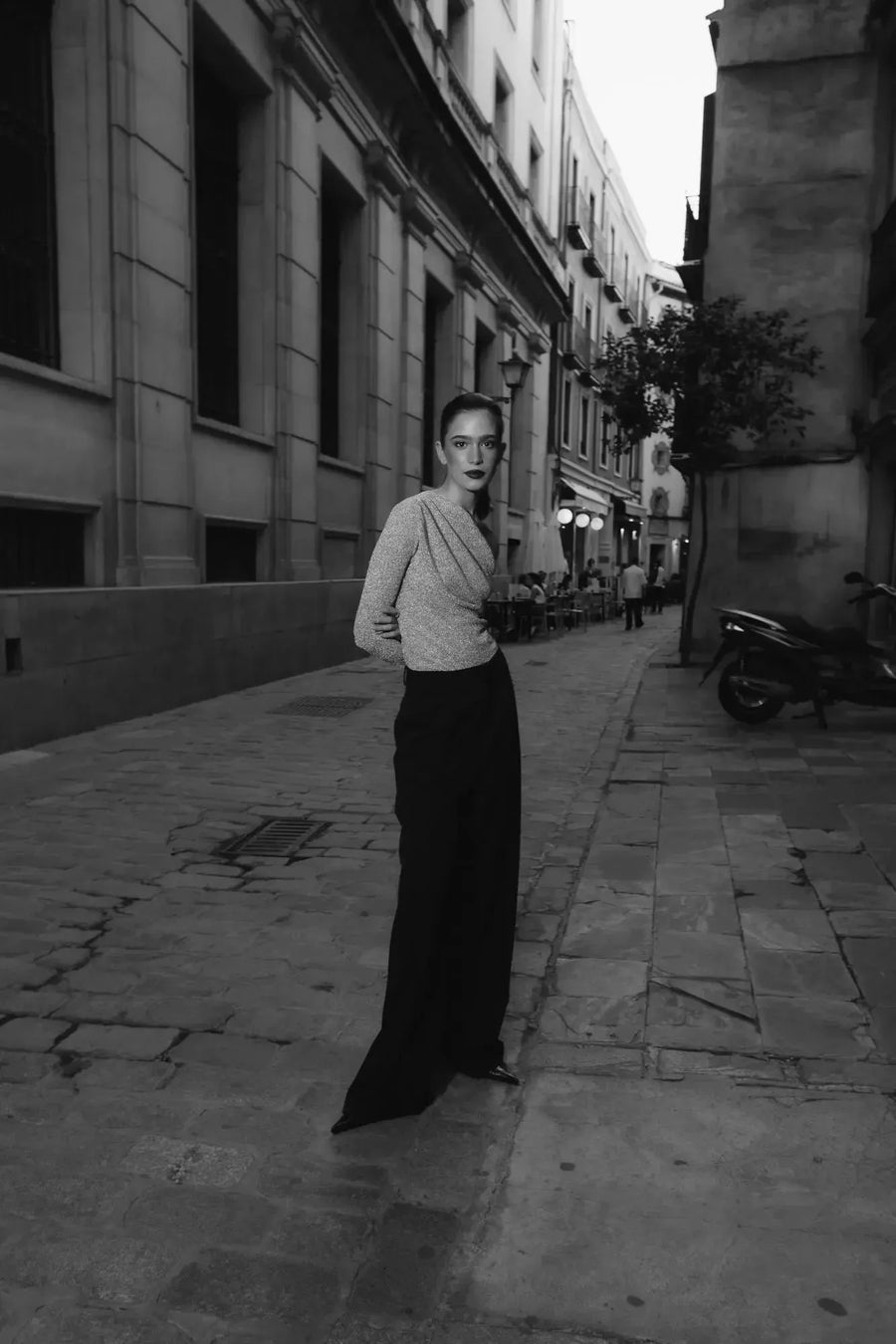 Siluette élégante en noir et blanc d'une femme en body asymétrique, marchant dans une rue pavée, incarnant le style et le confort.