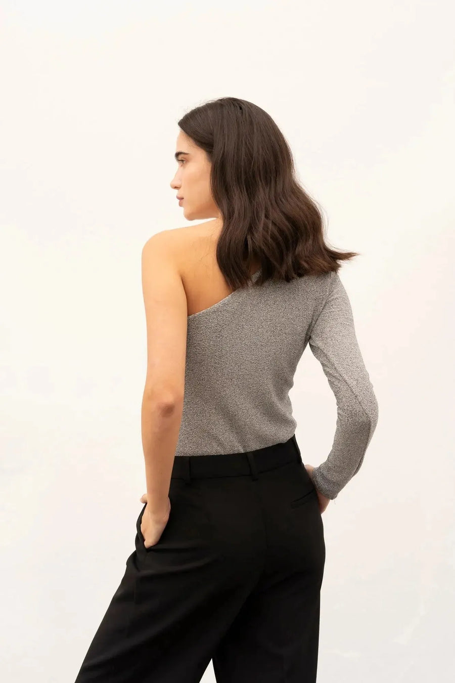Vue côté d'une femme en body asymétrique, soulignant le design asymétrique et le confort de la pièce.
