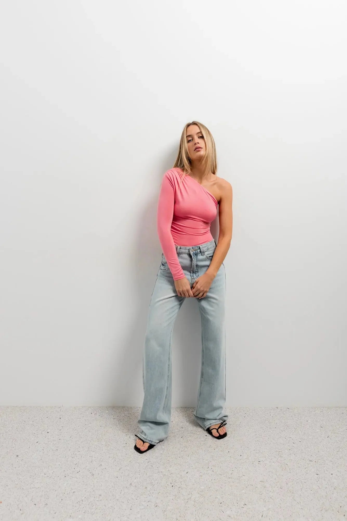 Vêtement body asymétrique vert avec manche longue, top rose clair et jeans wide-leg
