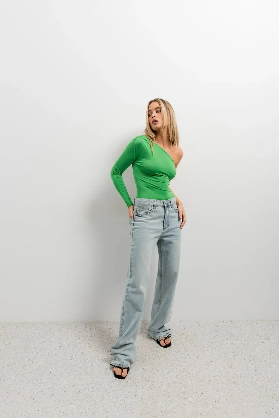 Body vert femme asymétrique à manches longues - Élégance et confort pour toutes occasions, porté avec un jean décontracté.