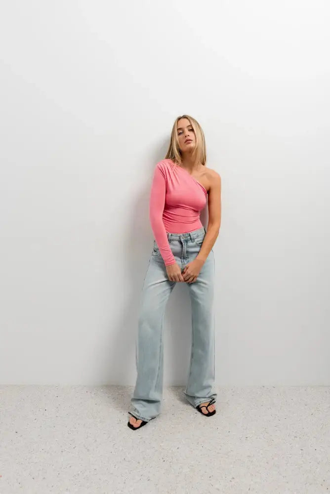 Vêtement body asymétrique vert avec manche longue, top rose clair et jeans wide-leg