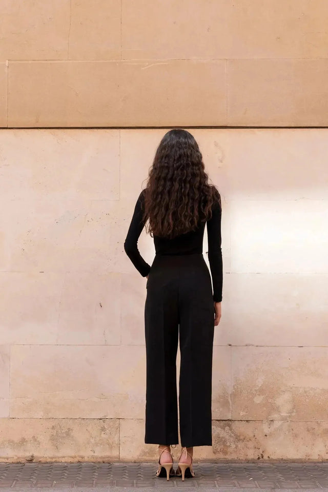 Vue arrière d'une femme en body manche longue femme chic noir drapé asymétrique avec une coiffure décontractée, illustrant son confort.