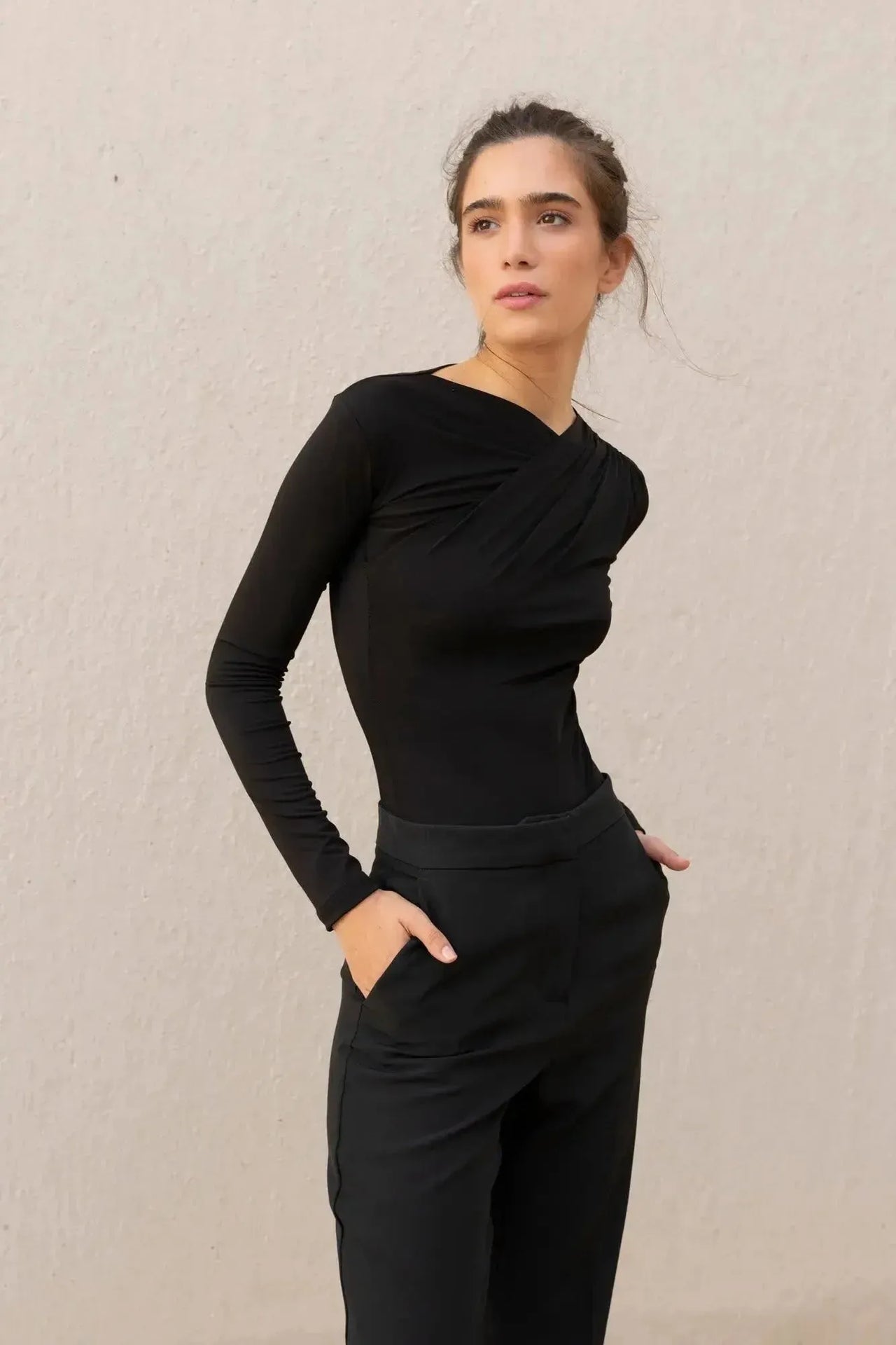 Femme en action dans un body manche longue femme chic noir drapé asymétrique, avec un look casual chic.