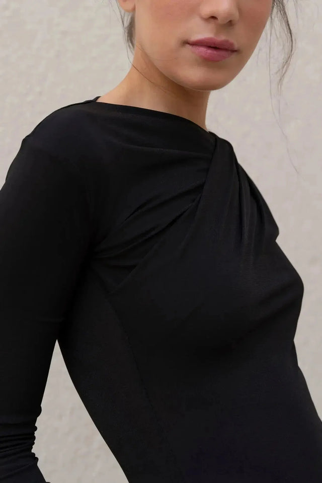 Zoom sur le décolleté d'un body manche longue femme chic noir drapé asymétrique, mettant en avant son tissu fluide et son design élégant.