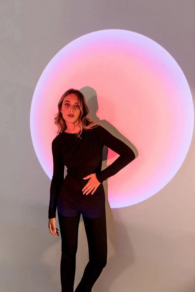 Body Drapé Noir Style et Confort Réunis - Femme posant devant un fond lumineux, vêtue d'un body manche longue femme, mettant en valeur le drapé sophistiqué.