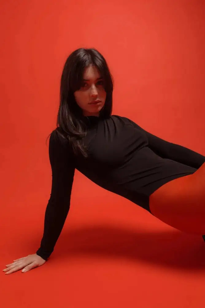 Femme en body drapé noir et pantalon rouge, style et confort réunis