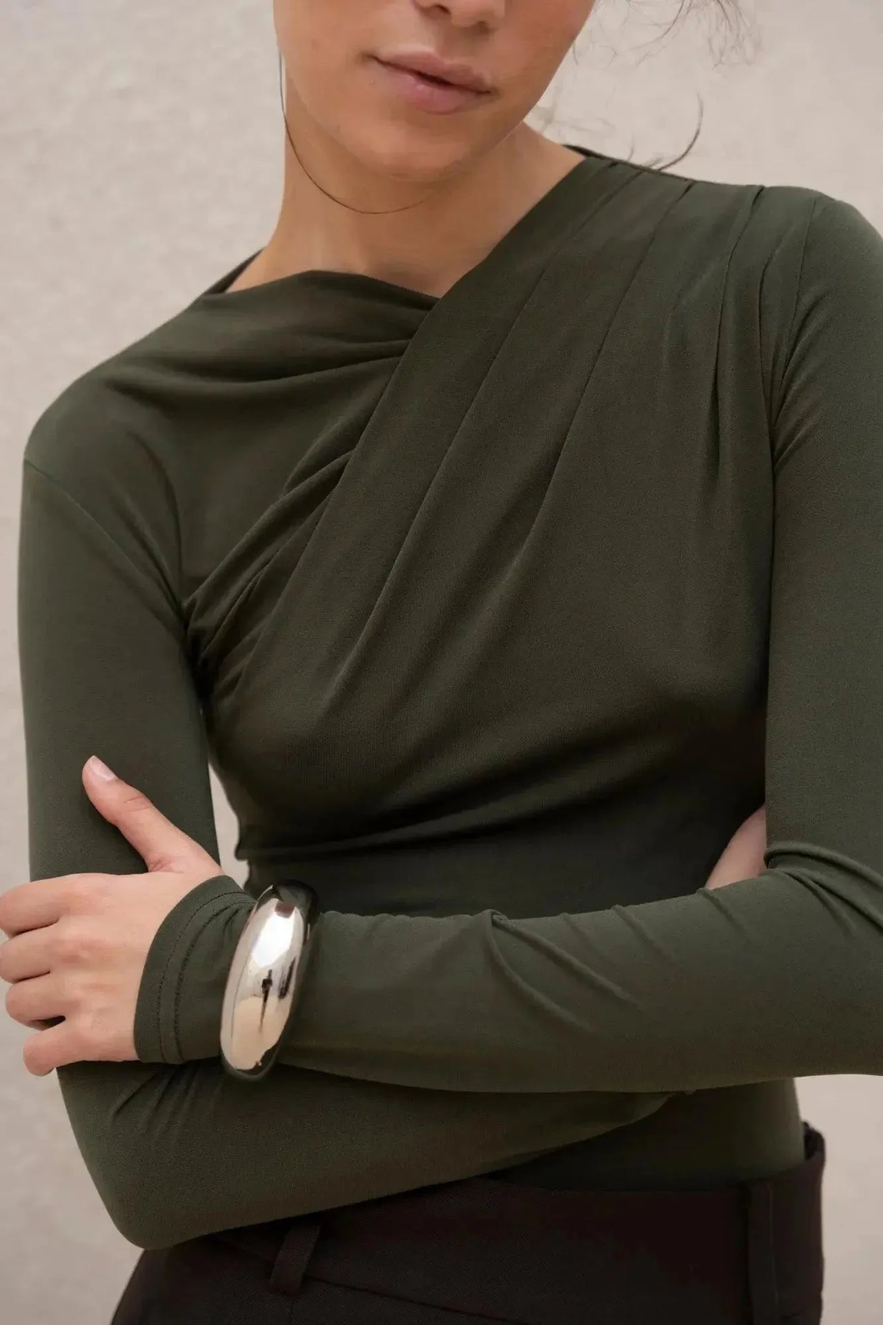 Détail du body vert élégant avec drapé, porté par un modèle, mettant en valeur la coupe asymétrique.