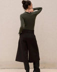 Modèle féminin avec un body vert olive asymétrique et pantalon noir, vue arrière.