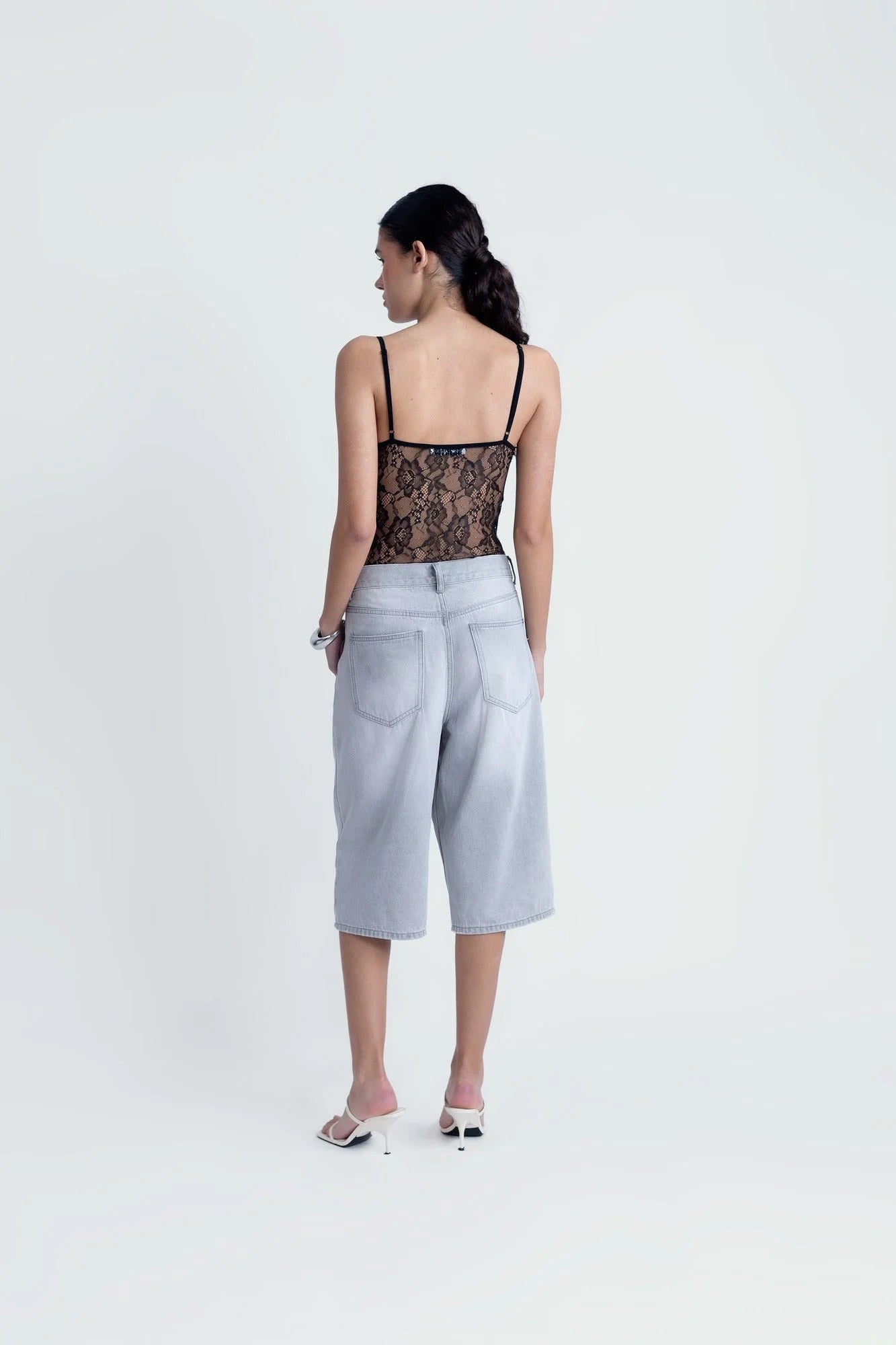 Body en dentelle noire à bretelles fines porté avec culottes en denim clair et mules blanches