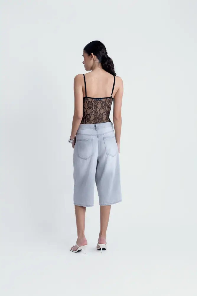 Body en dentelle noire à bretelles fines porté avec culottes en denim clair et mules blanches