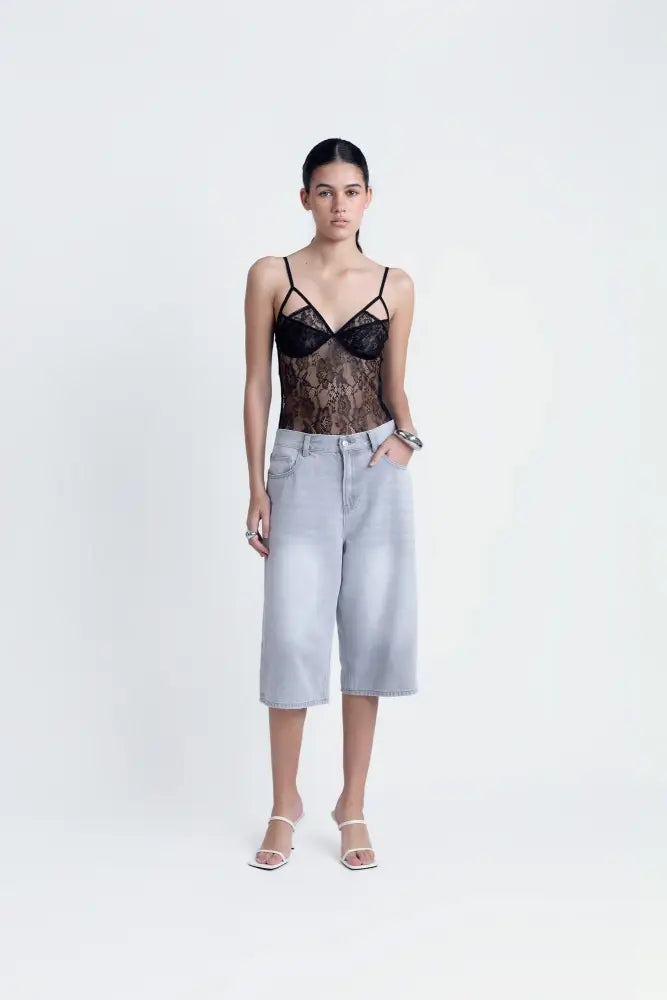 Body en dentelle noire à bretelles fines porté avec culottes en denim clair et talons hauts blancs