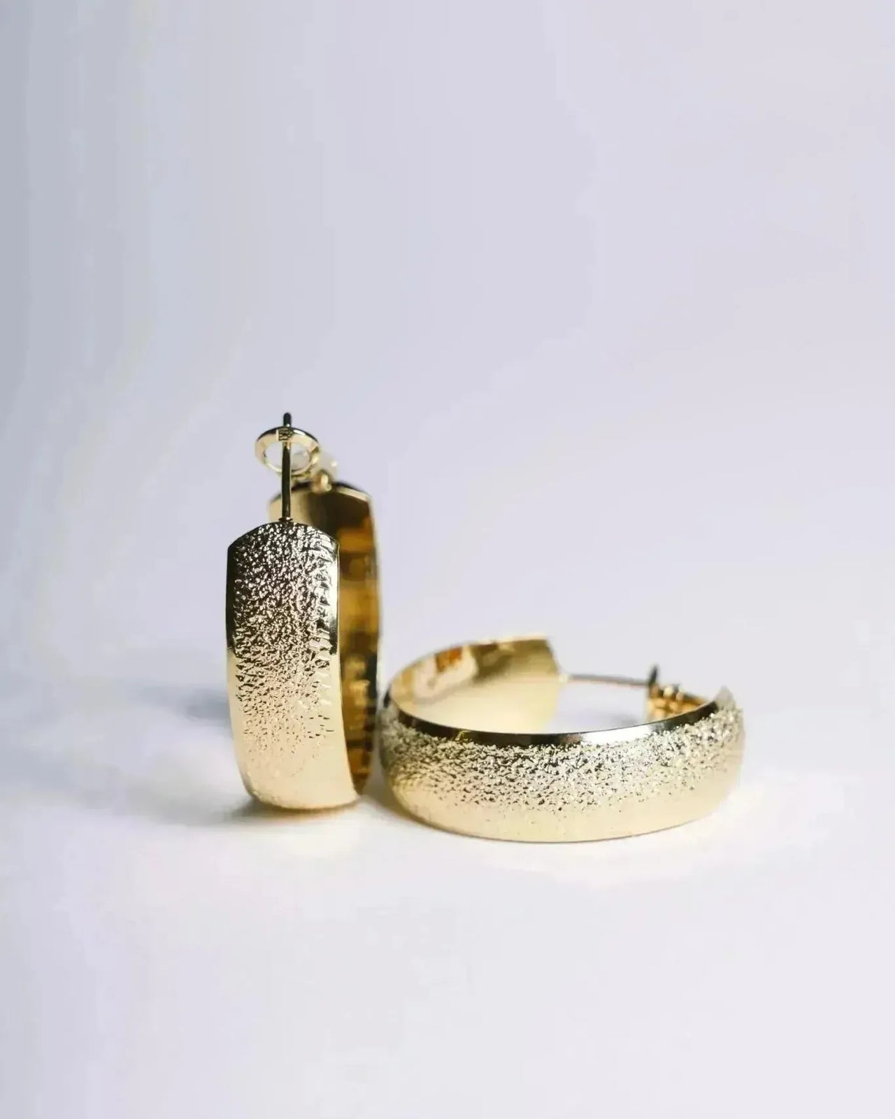 Deux boucles d'oreille plaqué or présentées sur un fond clair, illustrant leur design élégant et tendance. Élégance pour toutes les occasions.