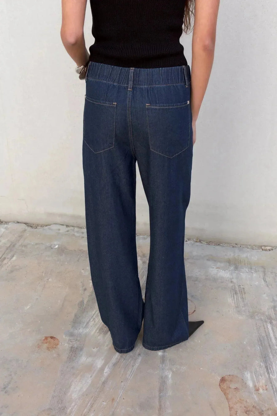 Détail arrière du pantalon fluide effet denim noir, jean élastique femme, accentuant les poches.