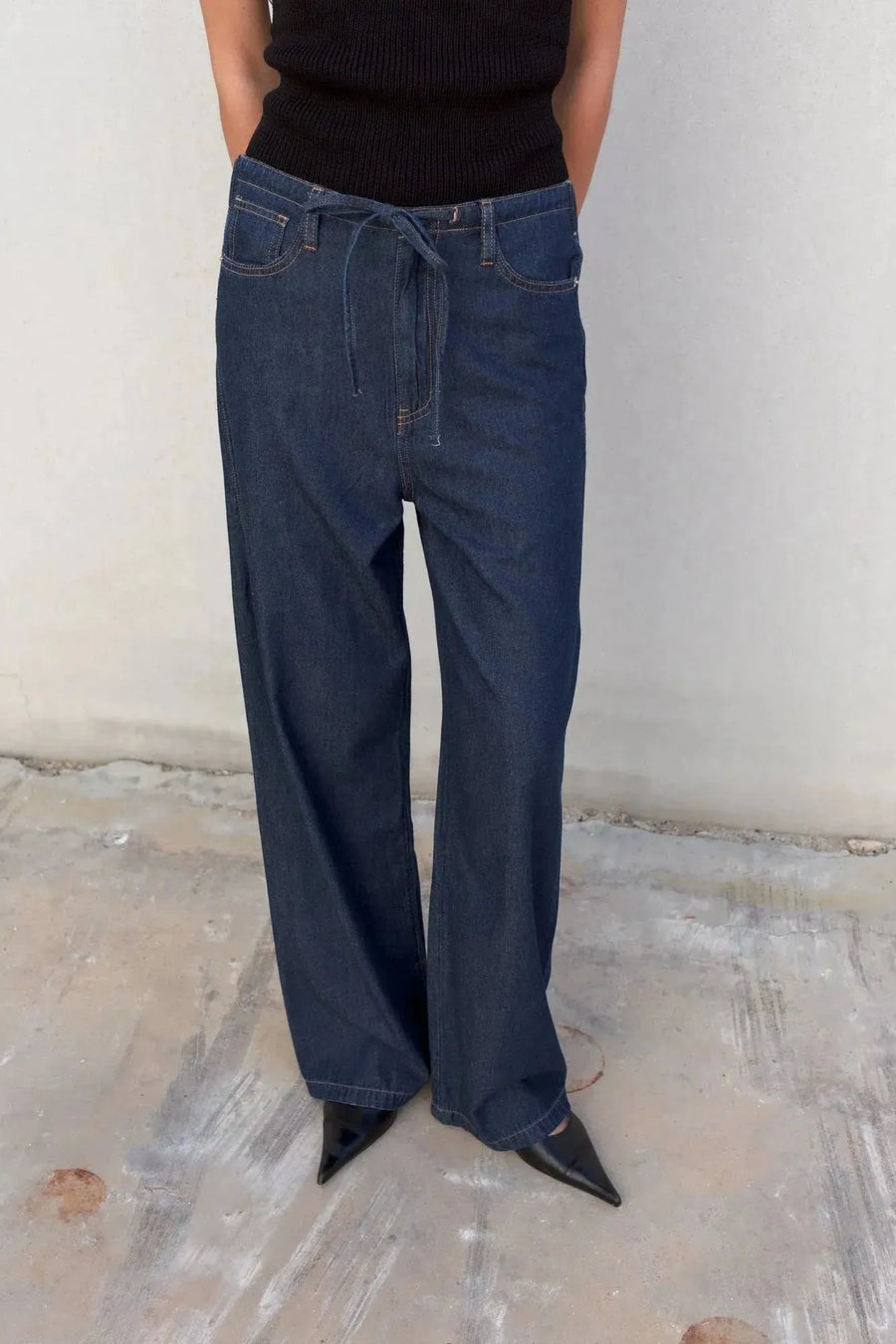 Femme en pantalon fluide effet denim noir, jean élastique femme, montrant un détail sur la taille.