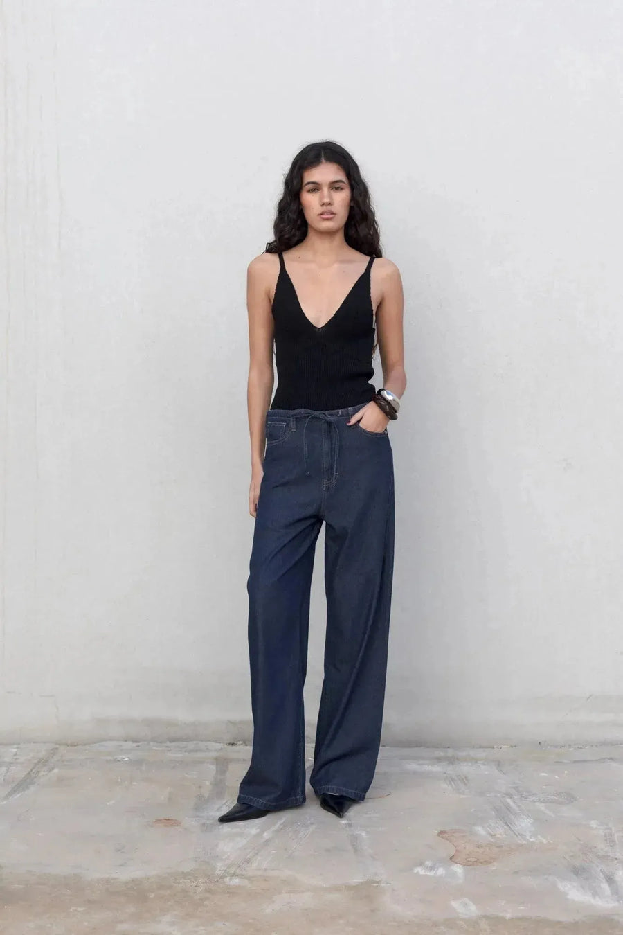 Femme en jean élastique femme, pantalon fluide effet denim noir, portant un haut noir avec une coupe décontractée.