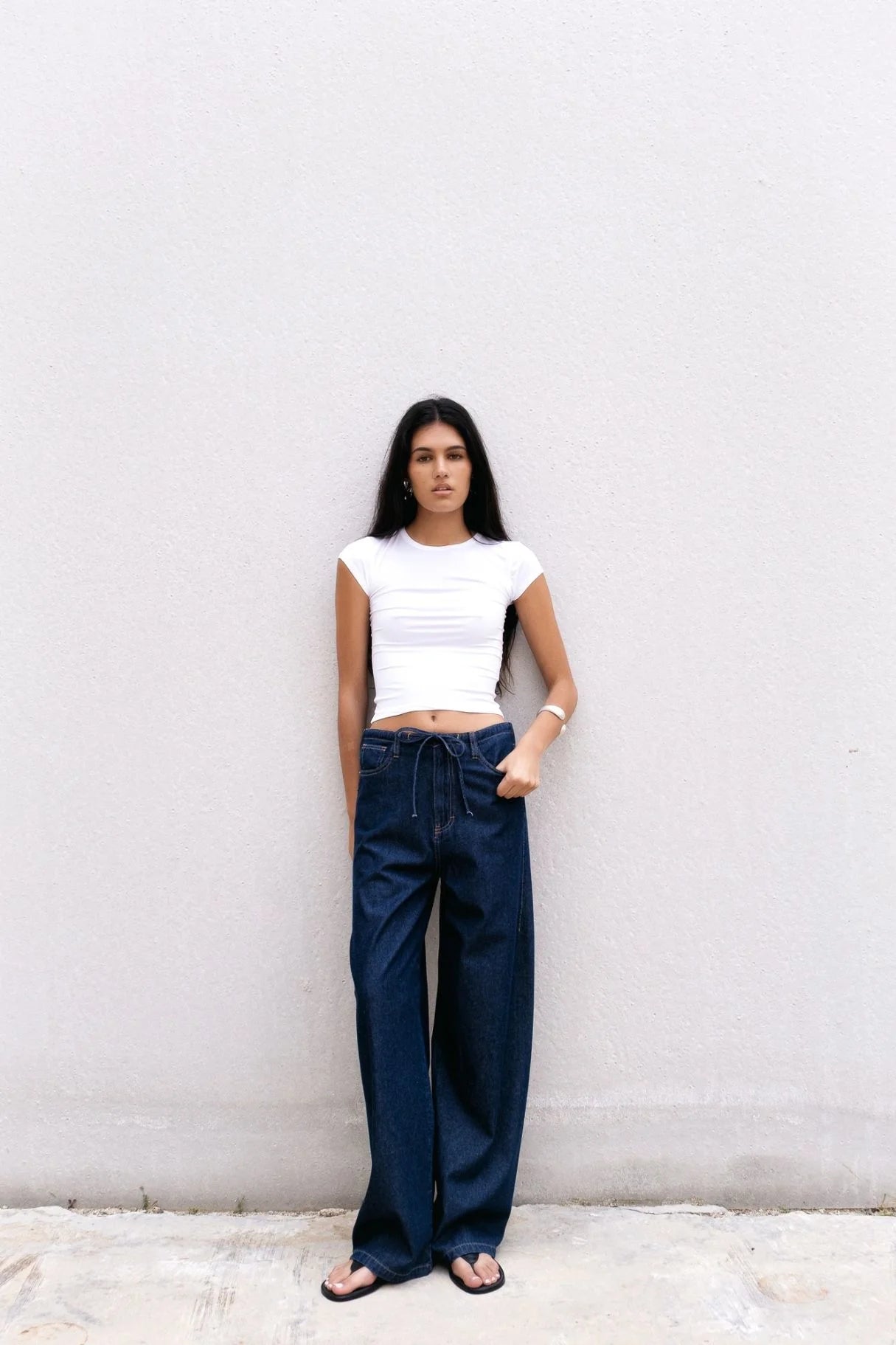 Femme portant un haut court blanc et un pantalon fluide effet denim bleu foncé