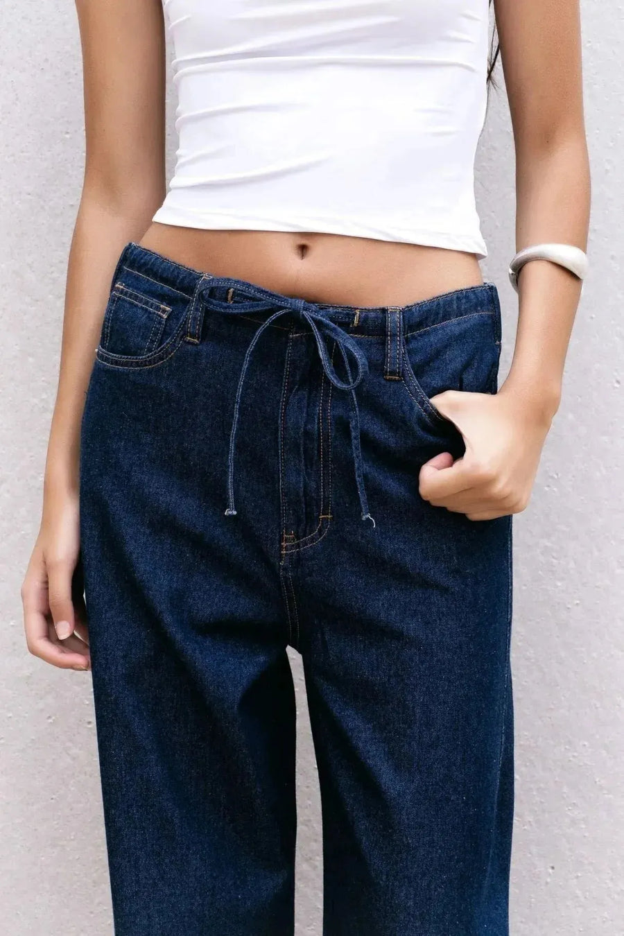 Détail du pantalon fluide effet denim noir, jean élastique femme, avec un lien à la taille.
