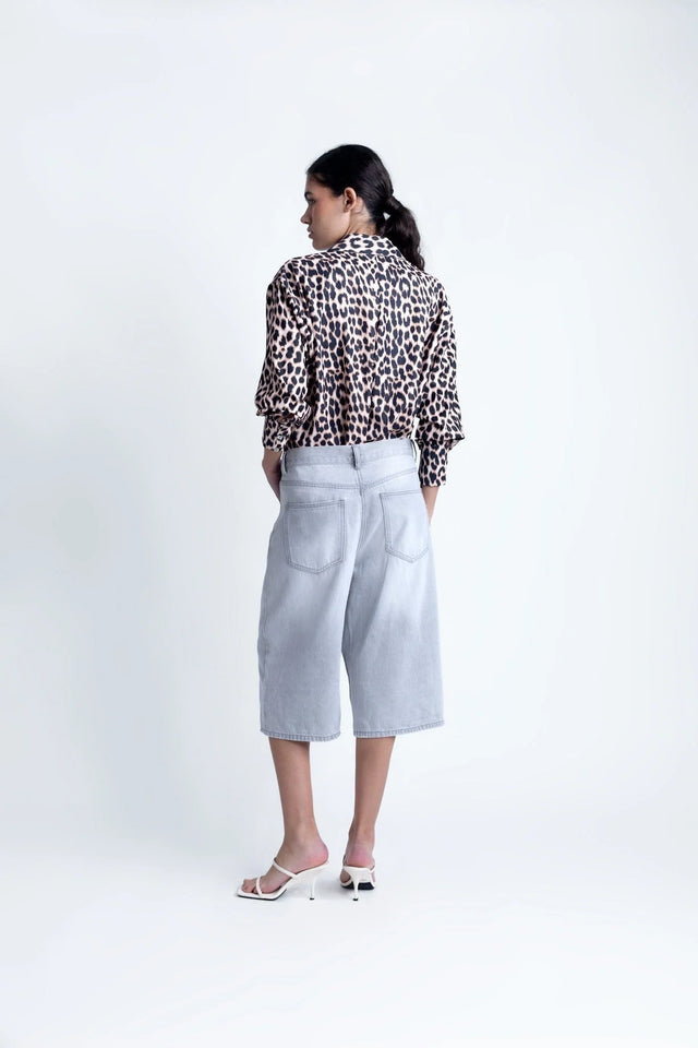 Vue arrière d'une femme portant une chemise à imprimé léopard à manches longues, associée à un pantalon confortable. Chemise longue leopard femme.