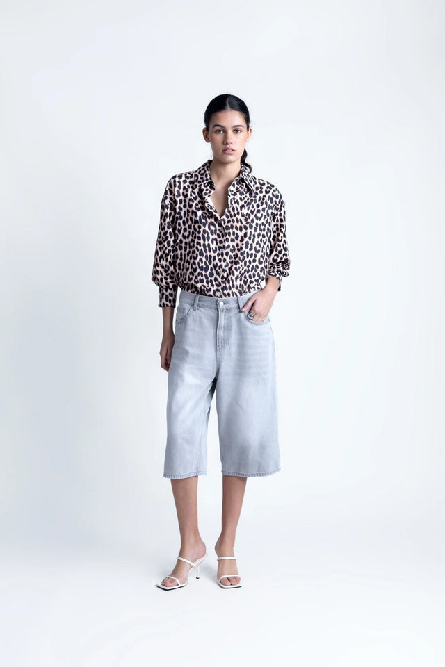 Femme présentant une chemise à imprimé léopard à manches longues avec un look élégant, portée avec un pantalon ample. Chemise longue leopard femme.