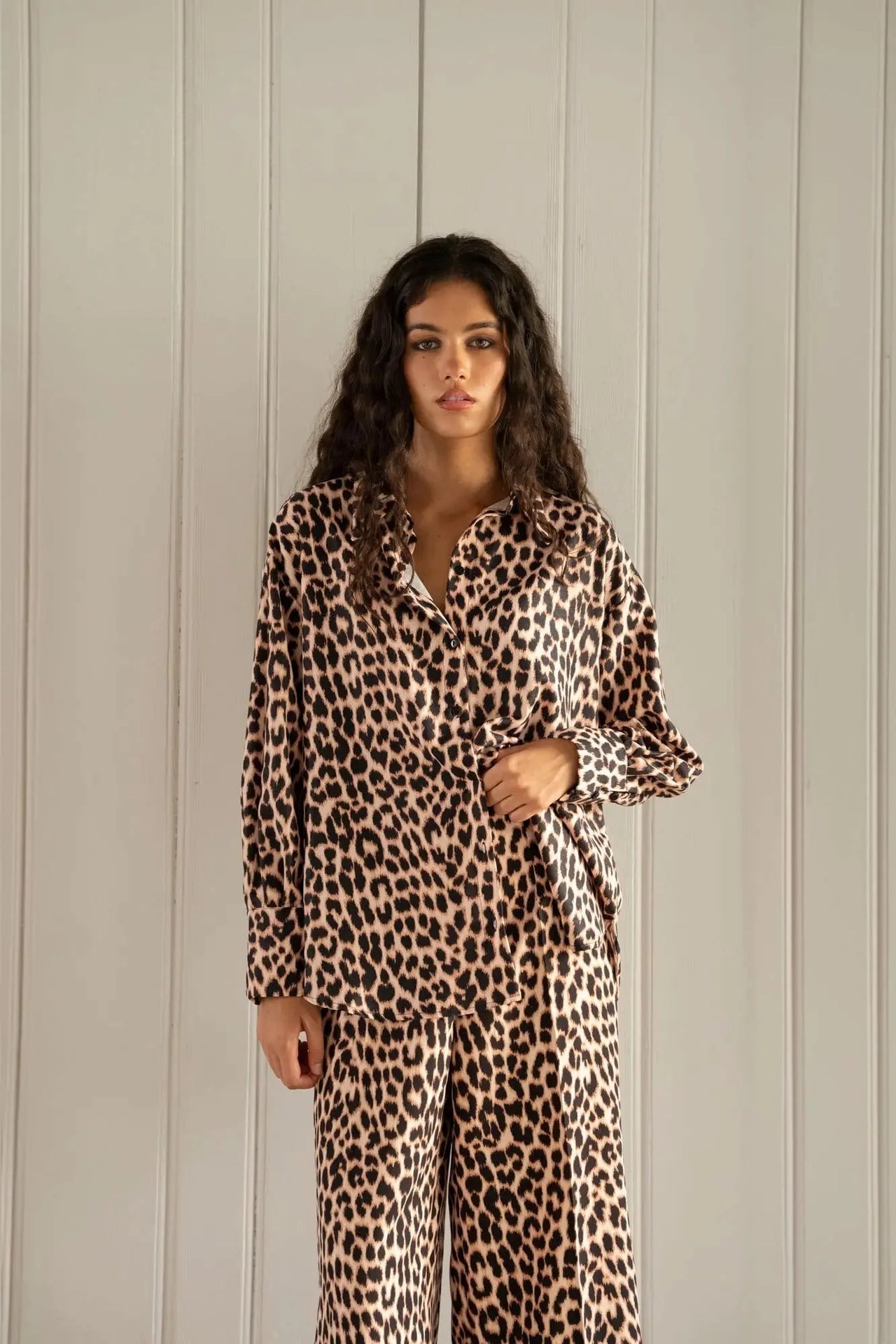 Gros plan d'une femme en chemise à imprimé léopard à manches longues, révélant un style chic et intemporel. Chemise longue leopard femme.