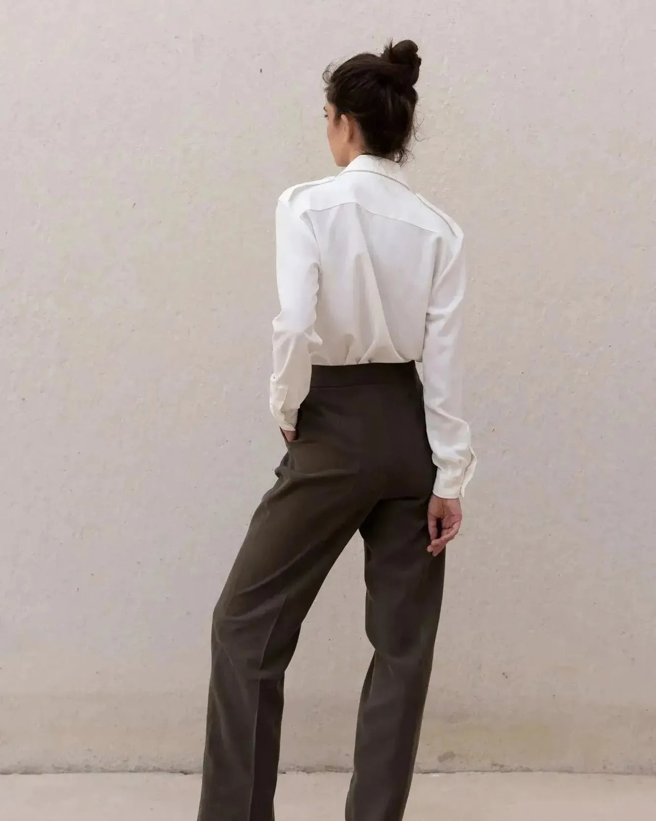 Vue arrière d'une femme avec une chemise blanche en soie à poches, montrant la coupe élégante, idéale pour combiner confort et style.